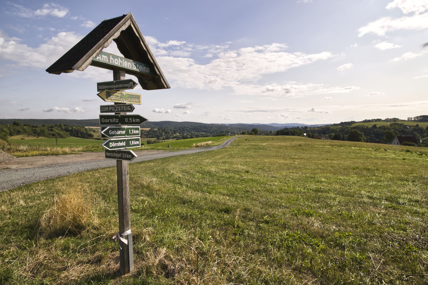 Wander-Wegweiser an der Stelle "Am hohlen Steine". Sehr weiter Panoramablick.